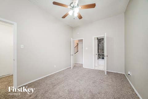 A spacious room with a ceiling fan and carpeted floor.