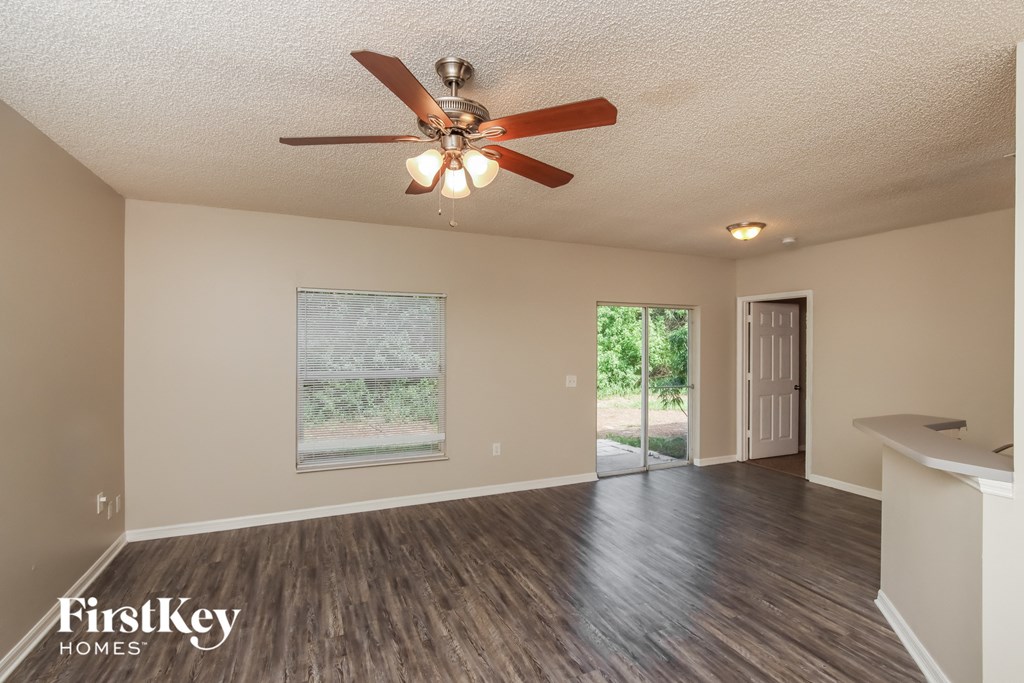 the spacious living room with ceiling fan and wood flooring
