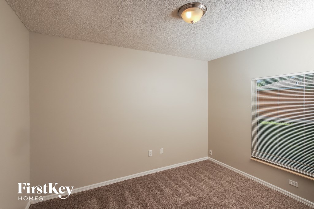 the upstairs bedroom has a large window and carpeted flooring