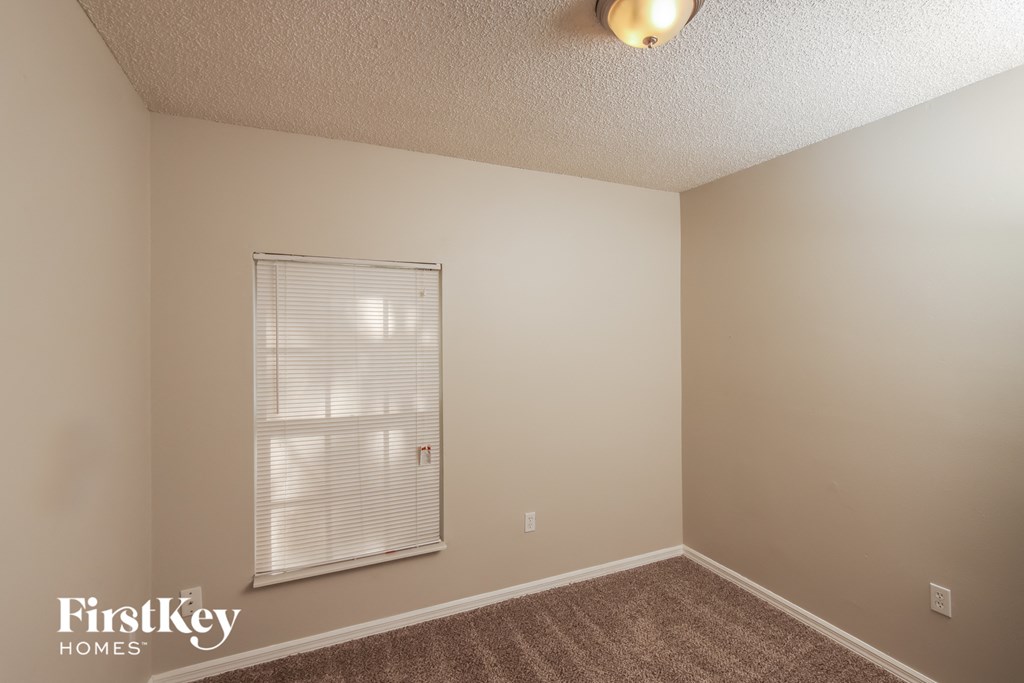 the upstairs bedroom has a large window and carpeted flooring