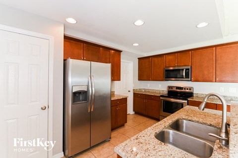 A kitchen with a stainless steel refrigerator and a granite countertop.