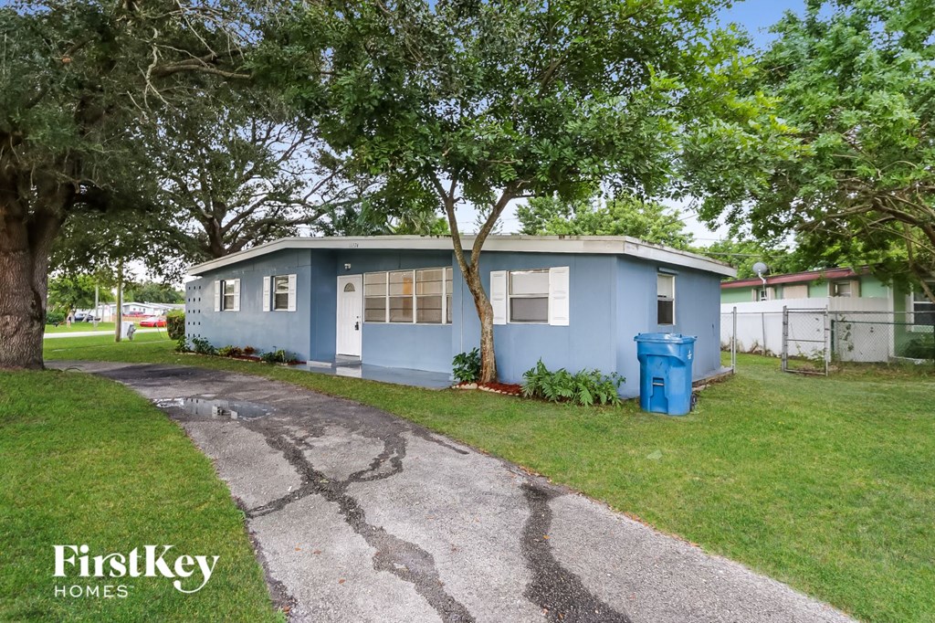 A blue house with a driveway in front of it.