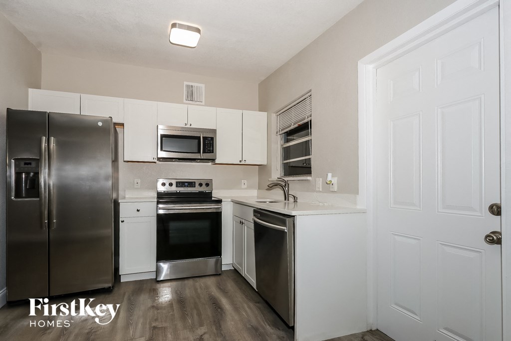 A kitchen with a refrigerator, oven, microwave, and sink.