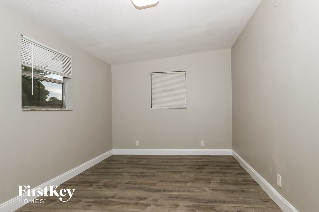 A room with wooden flooring and a window with blinds.