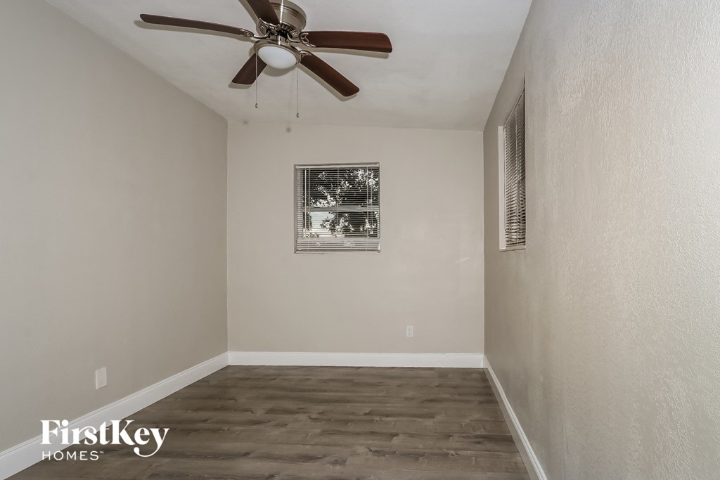 A room with a ceiling fan and a picture on the wall.