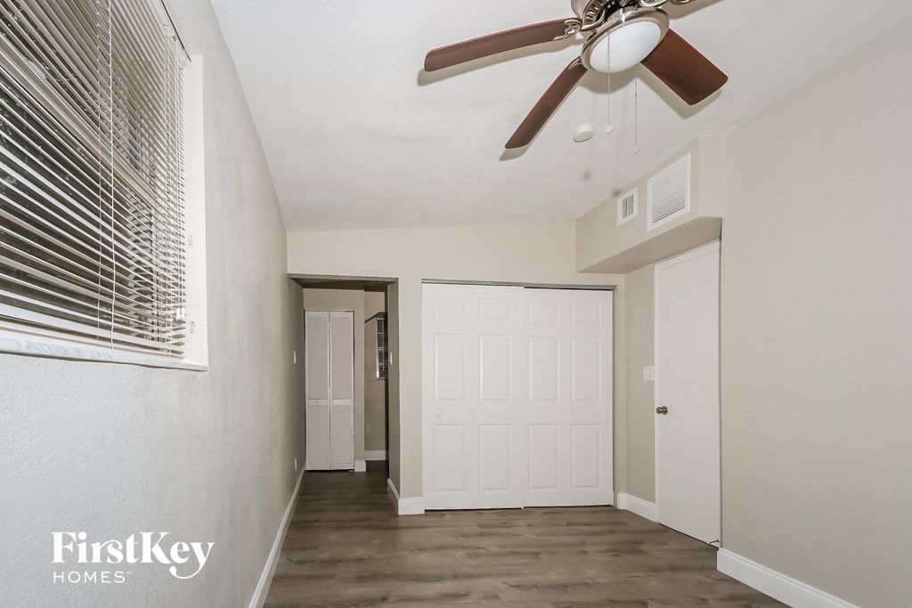 A spacious room with a ceiling fan and a window with blinds.