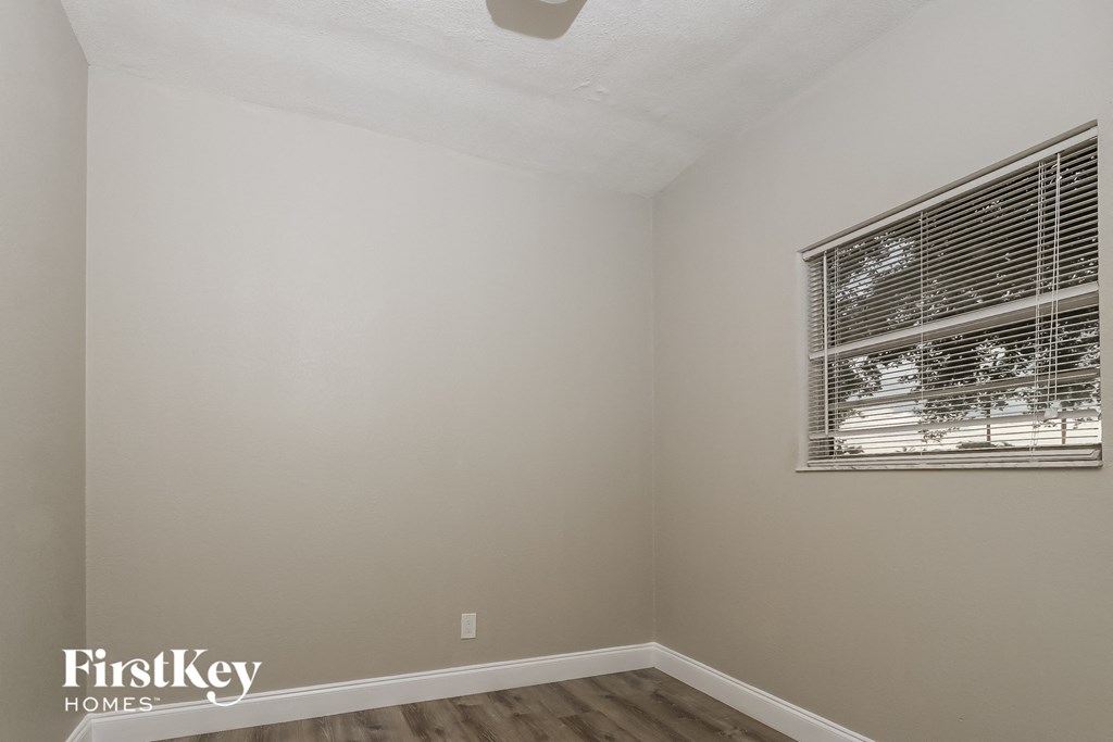 A room with a window covered by blinds and a FirstKey Homes logo on the wall.