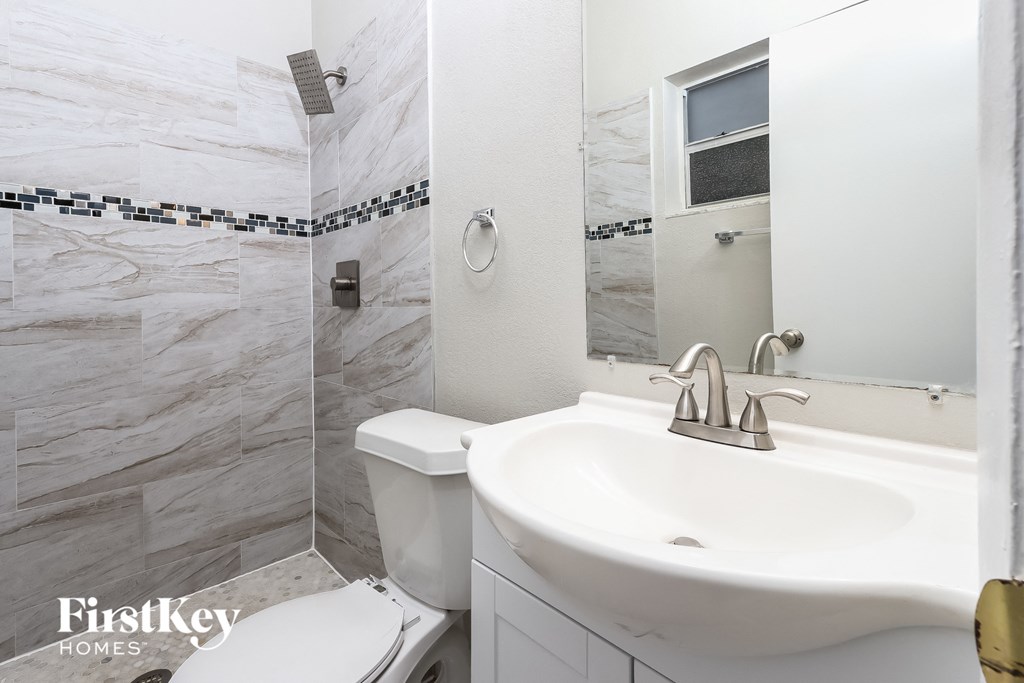 A bathroom with a marble tile wall and a white sink.