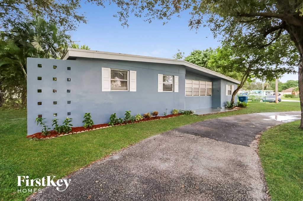 A blue house with a red border around the windows and plants in front.