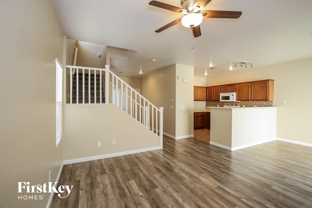 an open living room and kitchen with wood flooring and a ceiling fan