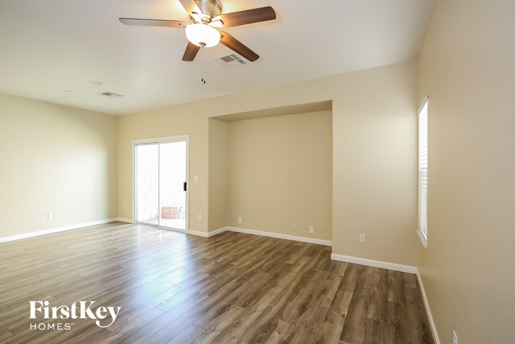 an empty living room with wood floors and a ceiling fan