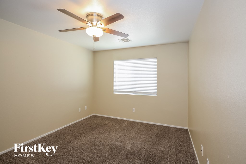 the spacious bedroom has a ceiling fan and a carpet