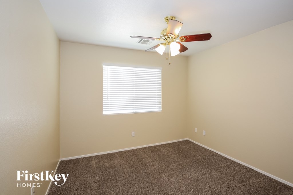a bedroom with a ceiling fan and a carpet