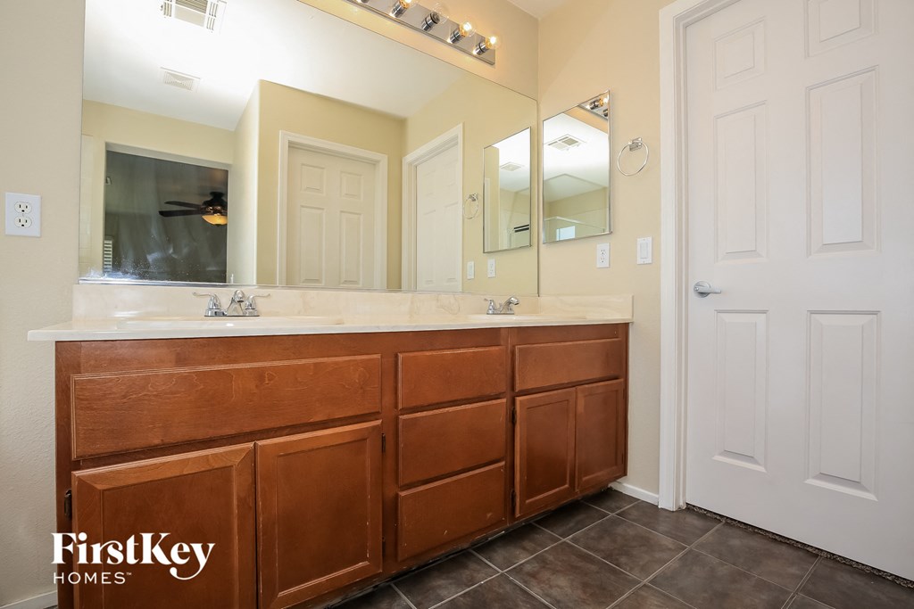the master bathroom has a large vanity with two sinks and a large mirror