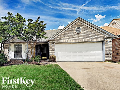 A house with a garage door and a tree in front of it.