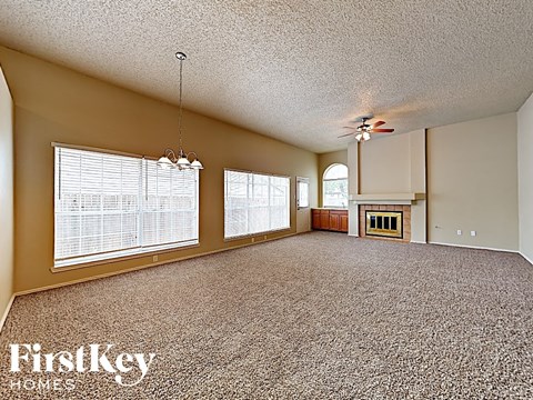 A spacious room with a carpeted floor and a ceiling fan.