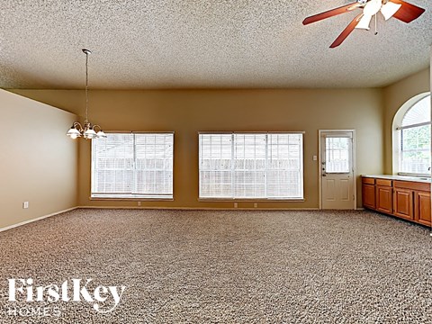 A spacious room with a ceiling fan and a carpeted floor.