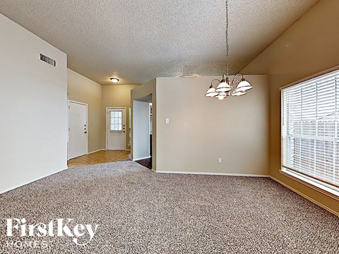 A spacious room with a carpeted floor and a window with blinds.