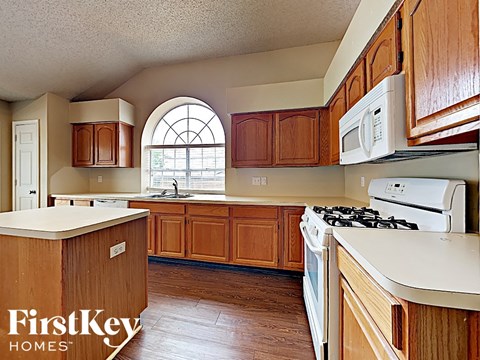 A kitchen with wooden cabinets and a white stove top oven.