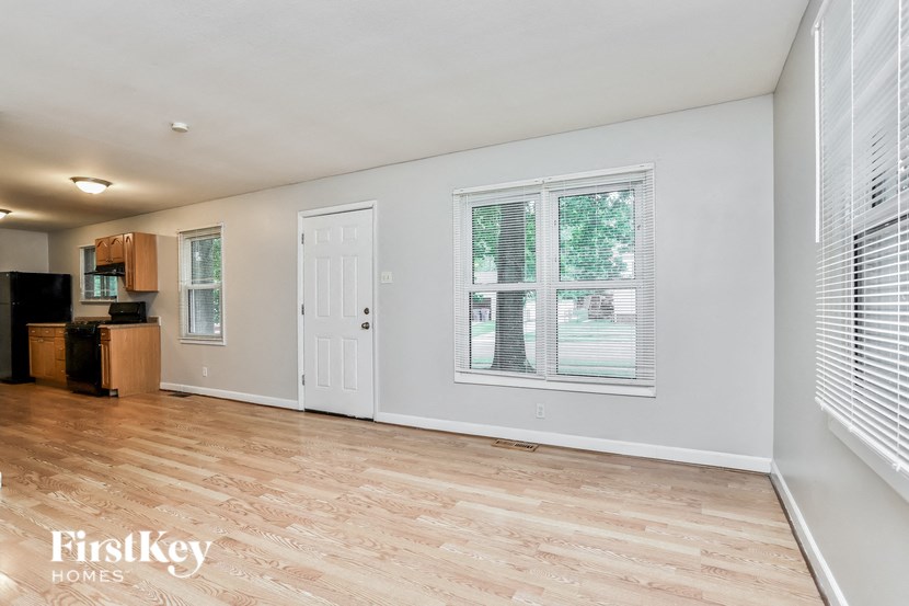 A spacious room with wooden flooring and a large window.
