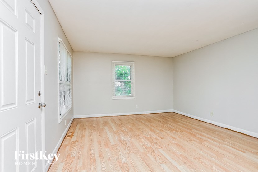 A room with wooden flooring and a window showing greenery outside.