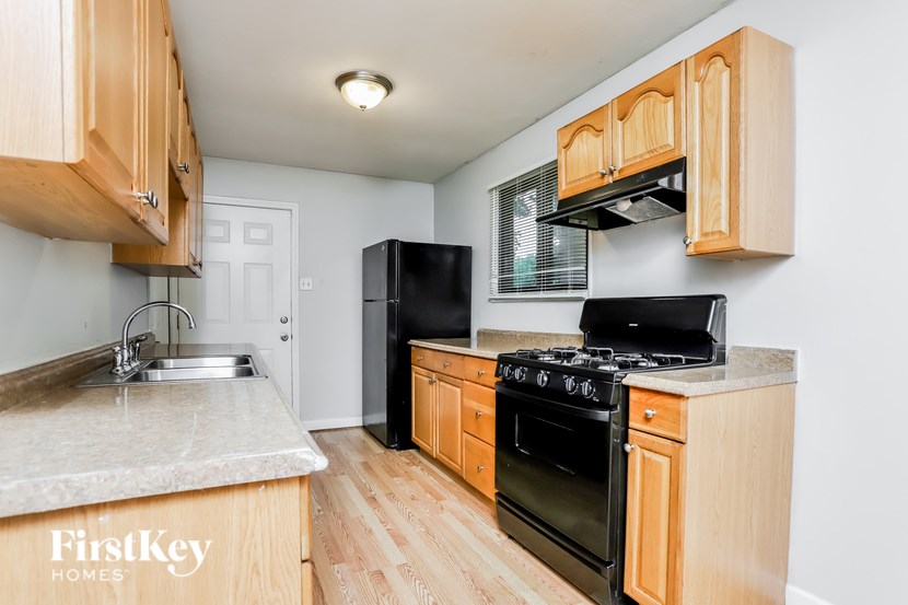 A kitchen with wooden cabinets and a black refrigerator.