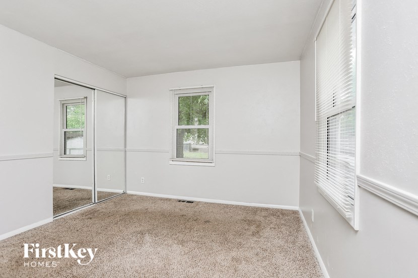 A room with a carpeted floor and a window with blinds.