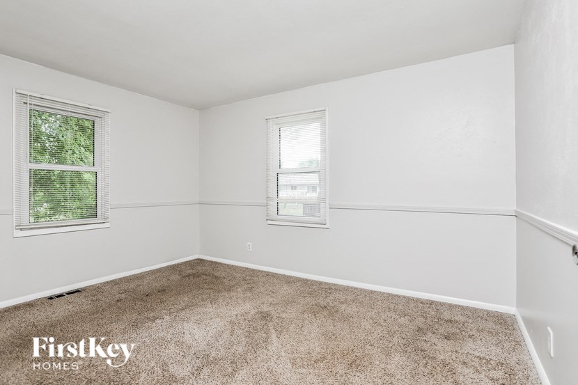 A room with a carpeted floor, two windows, and a FirstKey Homes logo.