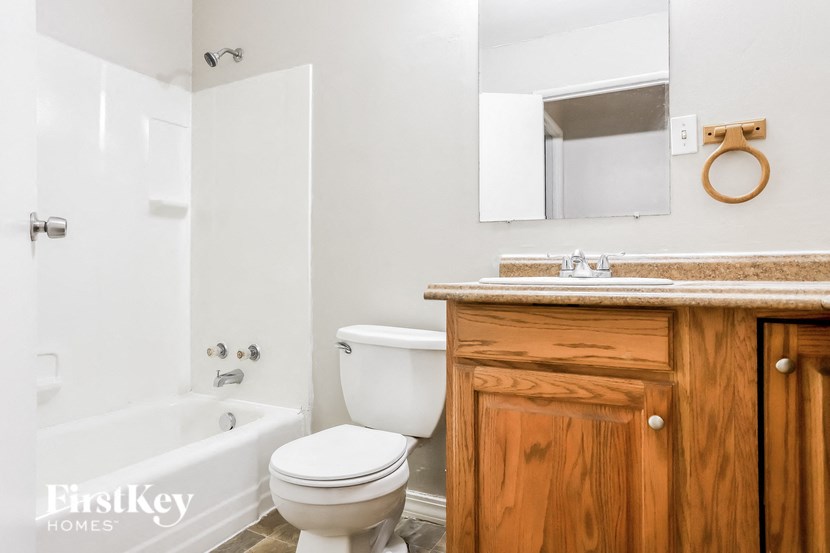 A white toilet sits next to a white bathtub in a bathroom.