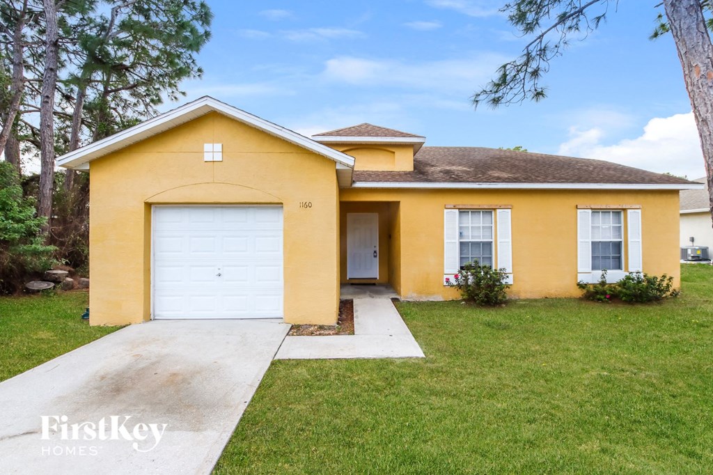 A yellow house with a white garage door and a brown roof.