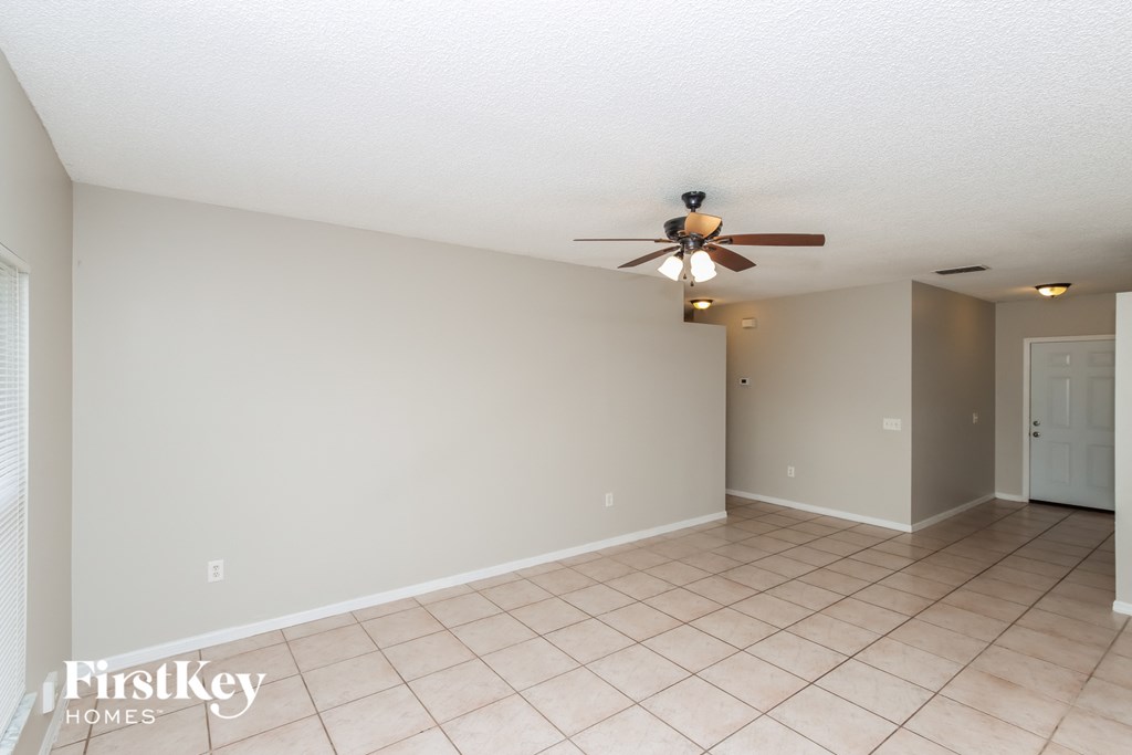 A spacious room with a ceiling fan and tiled floor.