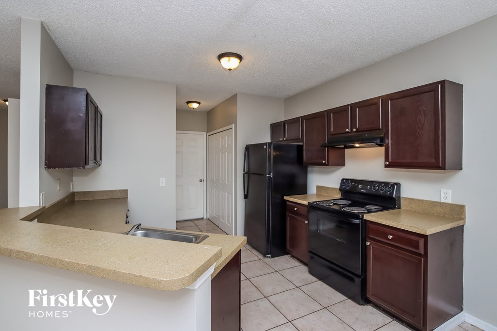 A kitchen with brown cabinets and black appliances.