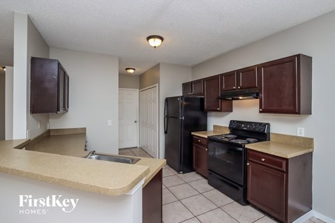 A kitchen with brown cabinets and black appliances.