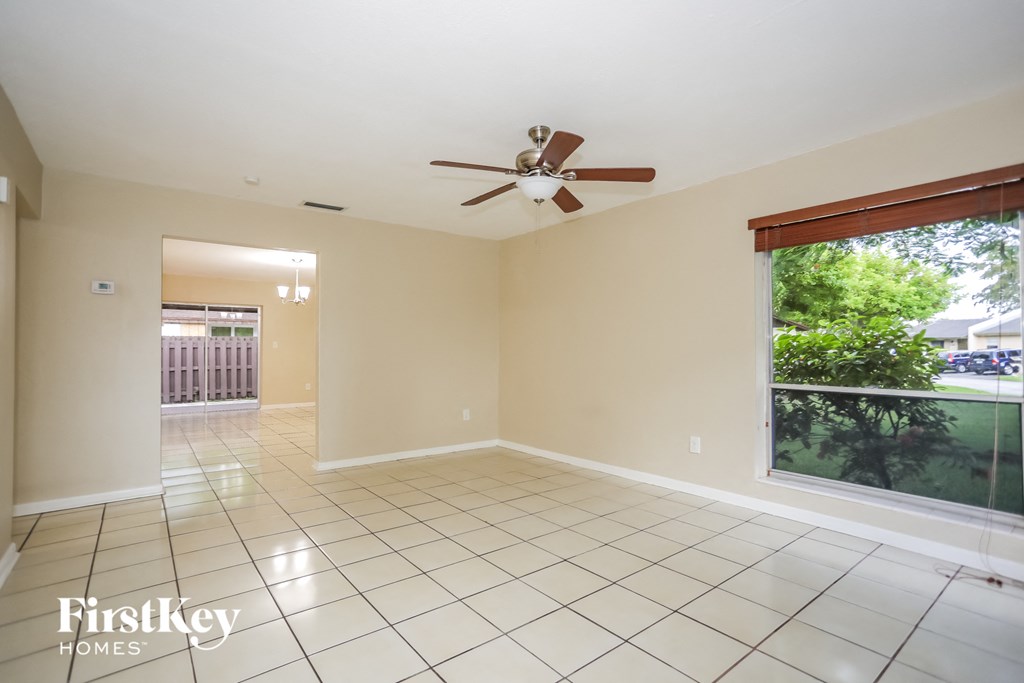 an empty living room with a ceiling fan and a large window