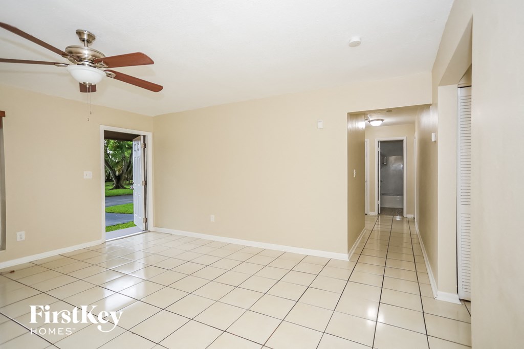 an empty living room with a ceiling fan and tiled floor