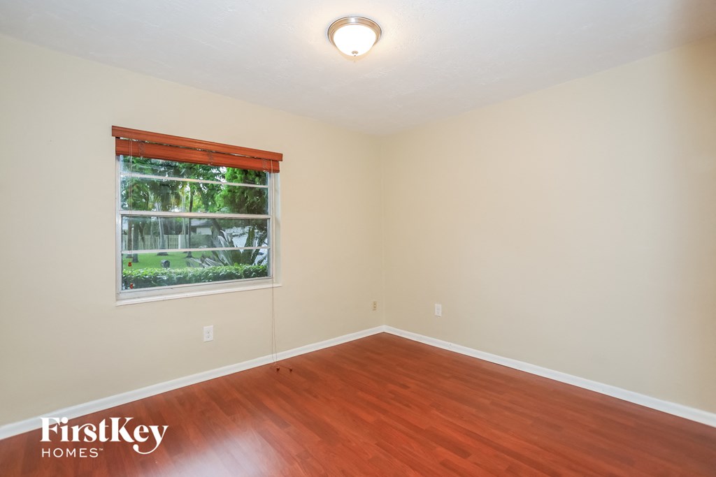 a bedroom with wood flooring and a window