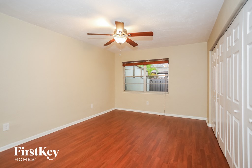 an empty living room with wood floors and a ceiling fan