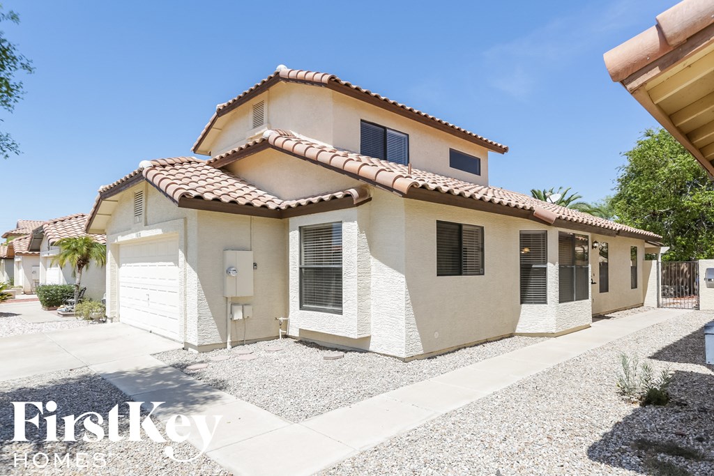a small white house with a tile roof and a driveway