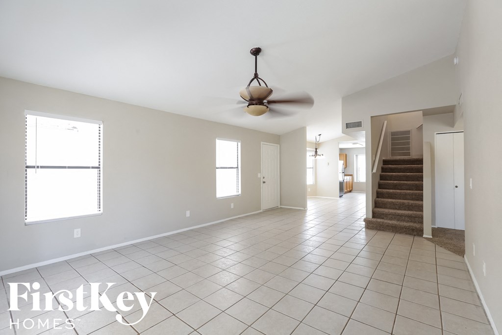 an empty living room with a ceiling fan and a staircase