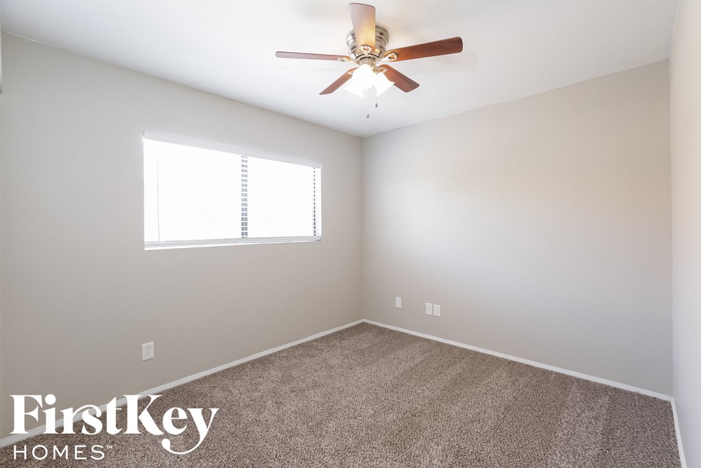 an empty room with a ceiling fan and a window