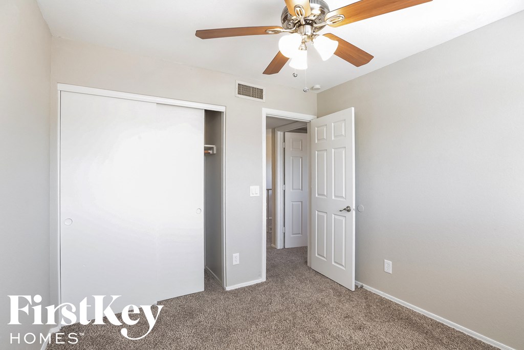 a bedroom with a ceiling fan and a door to a closet