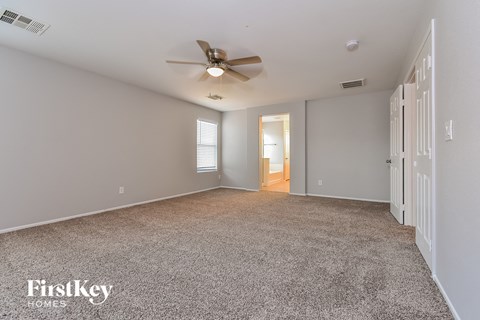a spacious living room with carpet and a ceiling fan
