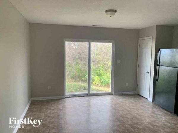 A room with a black fridge and a sliding glass door leading outside.