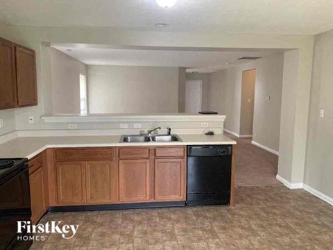 A kitchen with wooden cabinets and a black dishwasher.