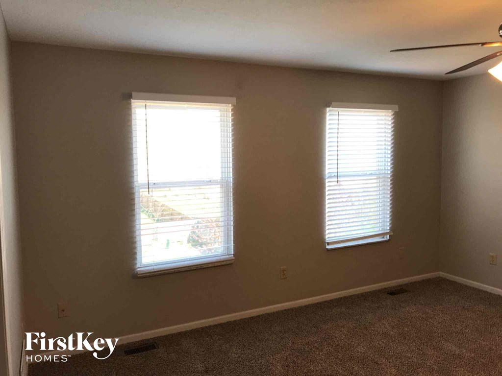 a living room with two windows and a ceiling fan