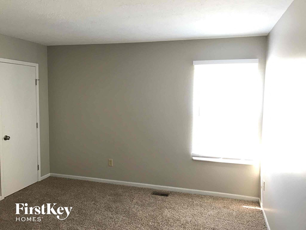 a blank wall in a room with a window and carpet