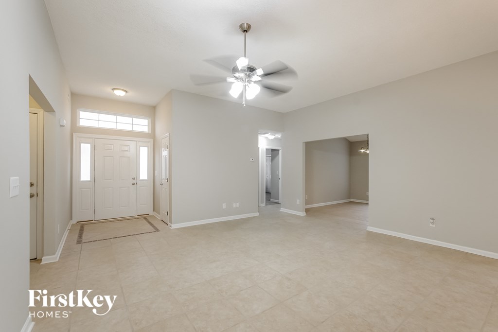 A spacious room with a fan and a rug on the floor.