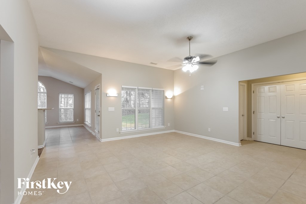 A spacious room with a ceiling fan and a large window.