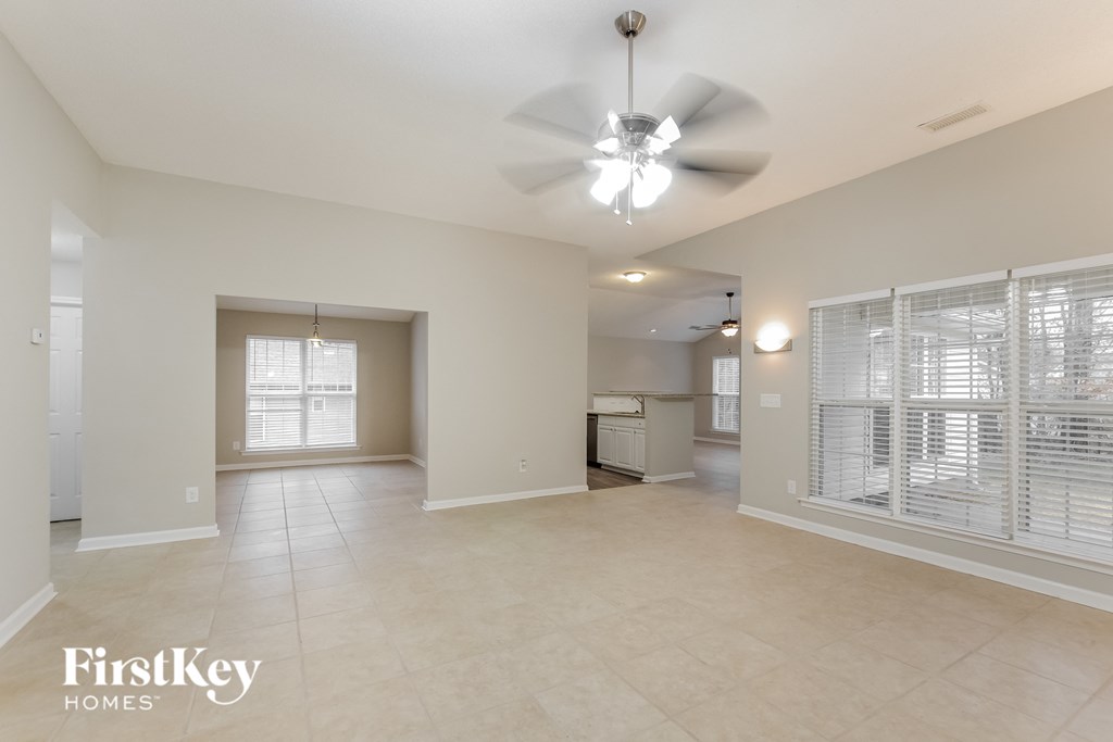 A spacious living room with a ceiling fan and a refrigerator.