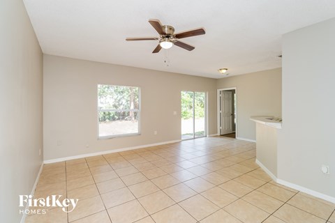 A spacious room with a ceiling fan and tiled flooring.